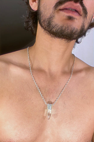 A lingam shaped hanging crystal quartz pendant on a silver neck chain. 