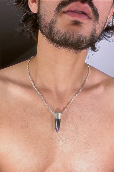 A lingam shaped hanging Amethyst crystal pendant on a silver neck chain. 