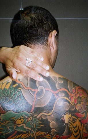 a koi star spinner ring on an indian boy with a back full of colorful tattoos. 